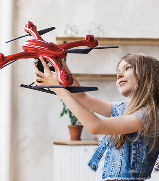 Young cute girl holding quadcopter at home  Child playing with drone  Education, home studying, children, technology, science, future and people concept