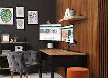 Comfortable workplace with computer near wooden wall in stylish room interior. Home office design